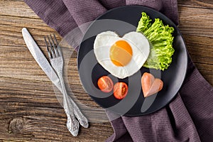 Valentines day breakfast with heart shaped fried eggs served on grey plate
