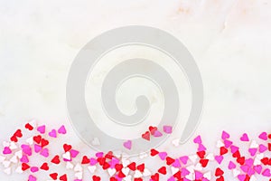 Valentines Day candy heart sprinkles bottom border over a white textured background