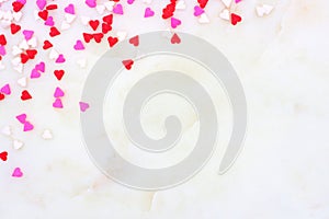 Valentines Day candy heart sprinkles corner border over a white textured background