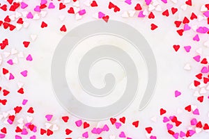 Valentines Day candy heart sprinkles frame over a white textured background