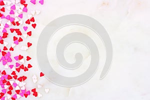 Valentines Day candy heart sprinkles side border over a white textured background