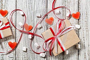 Valentines Day candy hearts marshmallows and box of gifts in craft paper over white wooden background