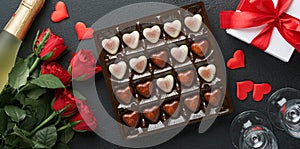 Valentines day card. Rose red flowers brownie cookies and chocolate candy on heart shaped, gift box with wine on black background.