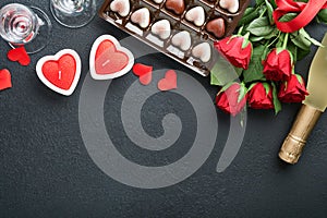 Valentines day card. Rose red flowers brownie cookies and chocolate candy on heart shaped, gift box with wine on black background.