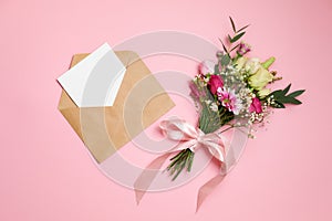 Valentines day composition: bouquet of flowers, kraft envelope with greeting card lay at pink background. Woman`s day card templa