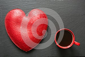 Valentines day composition with coffee cup and heart of red velvet cake on slate plate. Top view. Copy space.