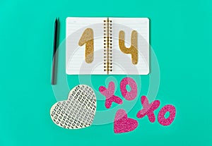 Valentines day composition. Turquoise background with notebook,pencil, gold numbers 14,letters XO and heart