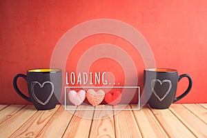 Valentines day concept with chalkboard coffee mugs, heart shapes and  loading love text on wooden table