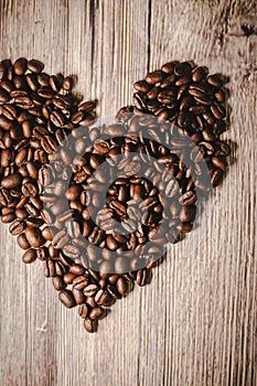 Valentines day concept: Coffee beans arranged in Heart Shape on wooden background