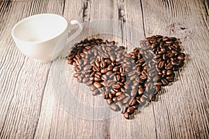 Valentines day concept: Coffee beans arranged in Heart Shape on wooden background