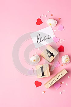 Valentines Day concept. February 14 wooden calendar, greeting card with the inscription love, pink and red hearts