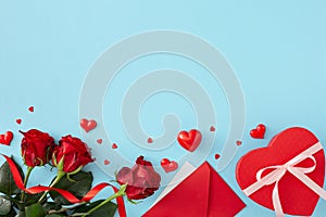 Valentines Day concept. Flat lay photo of red roses, hearts, envelope and heart shaped gift box on pastel blue background