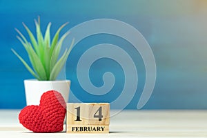 Valentines day concept. hand make yarn red heart beside wooden block calendar set on Valentines date 14 February in front of white