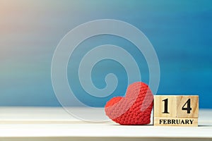 Valentines day concept. hand make yarn red heart beside wooden block calendar set on Valentines date 14 February on wooden table a