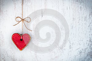 Valentines day concept. Heart shaped cookie tied with hemp bow over white wood rustic background.