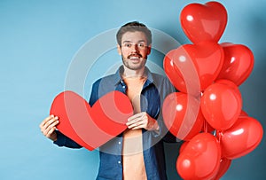 Valentines day concept. Man falling in love, looking startled at girlfriend, showing big red heart and standing near