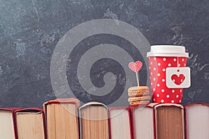 Valentines day concept with paper coffee cup, macarons and vintage books over blackboard