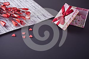 Valentines day concept with paper red flowers, candy sweet hearts, gift box and music sheet