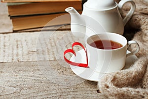 Valentines day concept with tea cup, papercraft heart and books on wooden vintage background, cozy weekend, hygge leisure concept