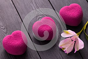 Valentines day concept. Three pink heart velvet cakes on a wooden black background with a delicate Alstroemeria flowers