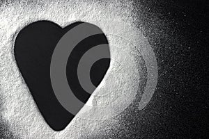 Valentines day concept white flour heart shape on black backround.