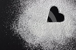 Valentines day concept white flour heart shape on black backround.