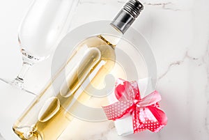 Valentines day concept with wine, two glasses and gift box on white marble background, copy space top view