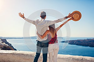 Valentines day. Couple in love enjoying view during honeymoon in Santorini island, Greece. People raising arms in Thera