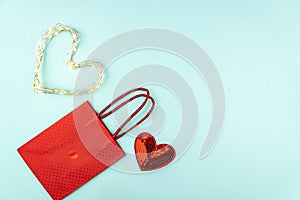 Valentines day creative concept. Red sequins heart, paper bag and heart shape led garand on blue background. Top view, flat lay,