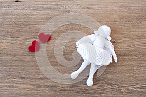 Valentines day crochet angel and two hearts on wooden table