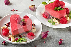 Valentines day dessert. heart shaped raw vegan red cakes with raspberries, dried rose flowers and mint. healthy food