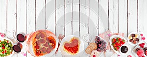 Valentines Day dinner bottom border on a white wood banner background with heart shaped pizza, pasta, wine, cheese plate, desserts