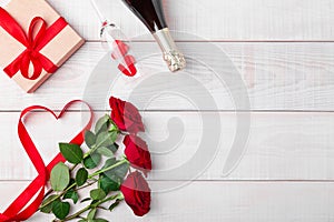 Valentines day dinner romantic setting, red tape, kraft gift box, heart in wine glass, champagne bottle, roses, on white