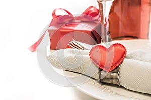Valentines day dinner with table place setting with red gift, heart with silverware on white background. Close up. Valentine`s ca