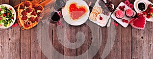 Valentines Day dinner top border on a dark wood banner background with heart shaped pizza, pasta, wine, cheese plate and desserts