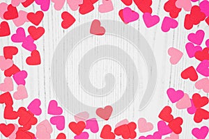 Valentines Day frame of heart confetti over a white wood background with copy space