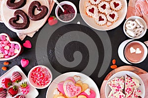 Valentines Day frame of mixed sweets and cookies, above view over a dark background with copy space