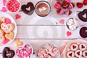Valentines Day frame with a selection of sweets and cookies, overhead view over a white wood background with copy space