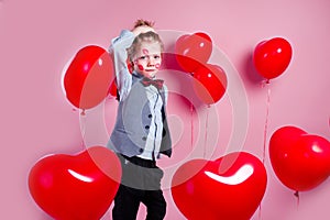Valentines day. Funny little boy with red kisses on the skin in red balloons in the shape of a heart photo
