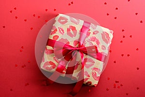 Valentines Day gift box with red ribbon on red background decorated heart shaped confetti. Flat lay, top view. Love and romance