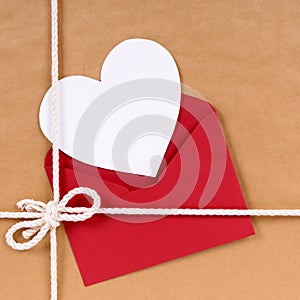 Valentines day gift with white heart shape card, red envelope, brown paper package parcel background