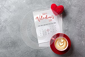 Valentines day greeting card. Coffee cup and gift box over february calendar on stone table. Top view with space for your