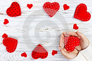 Girl holding a red heart. Valentines day greeting card. Handmaded hearts on wooden table. Top view with copy space photo