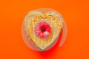 Valentines day greeting postcard. Gerbera flower on wicker texture on coral background.