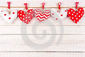 Valentines Day handmade cloth heart pillows on a line over white wood