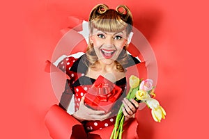 Valentines day. Happy woman with gift and flower looking through paper. Pin up girl with present.