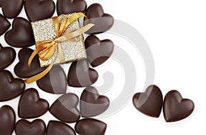 Valentines day, heart shaped chocolates with wrapped glittering golden box and shiny ribbon bow isolated on white background,