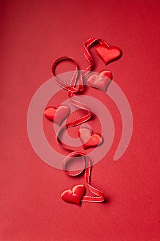 Valentines day hearts and ribbon on red background.