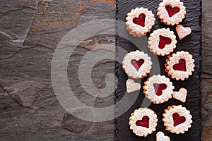 Valentines Day linzer jam cookies with heart shapes, side border on a slate serving platter with copy space