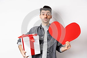 Valentines day and love concept. Guy waiting for kiss, bring lovely gifts and red heart card, pucker lips and look at